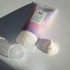 R+Co En una nube: empaque visible destacando ingredientes clave para brillo.