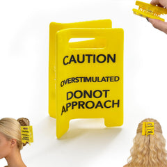 Pinza genérica para cabello con señal de precaución amarillo, ideal para expresar humor y practicidad